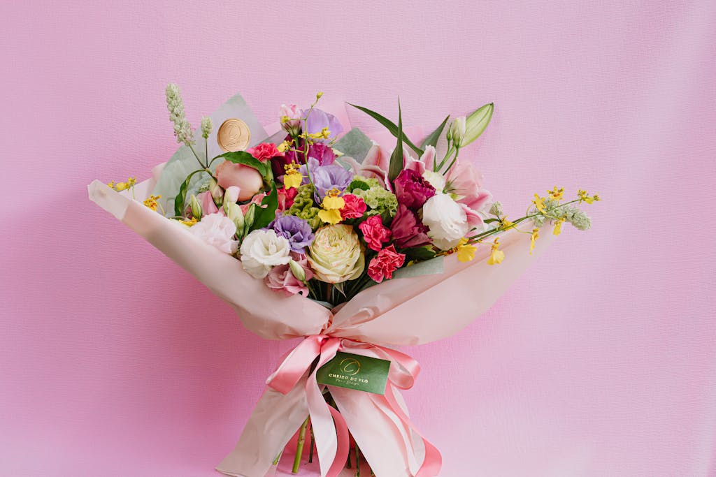 Charming mixed flower bouquet featuring roses and carnations against a pink backdrop.